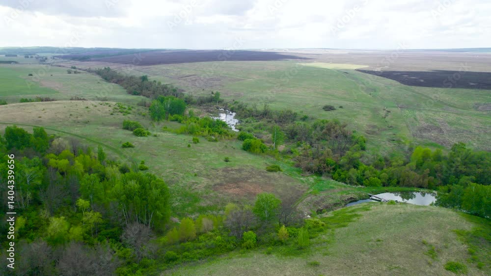 Winding river through green fields under cloudy sky Winding river through green fields under cloudy sky