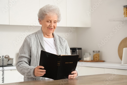 Senior woman reading Bible ...
