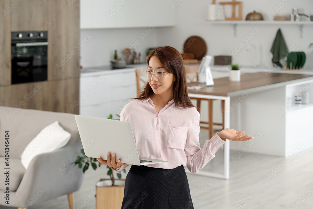Young Asian businesswoman working with laptop in kitchen Young Asian businesswoman working with laptop in kitchen