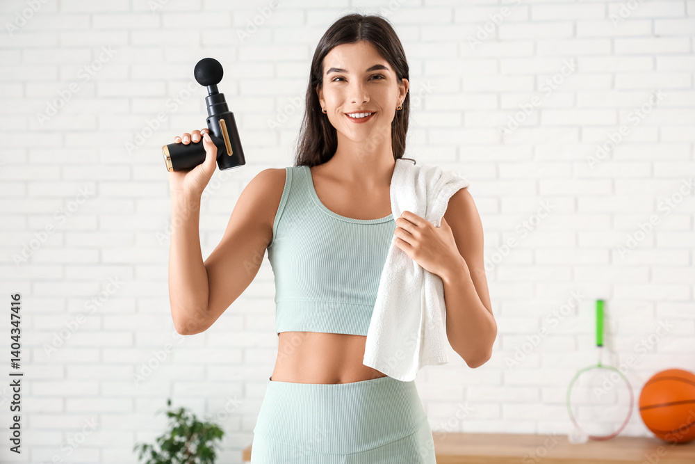 Fototapeta premium Sporty young woman with percussive massage device in gym