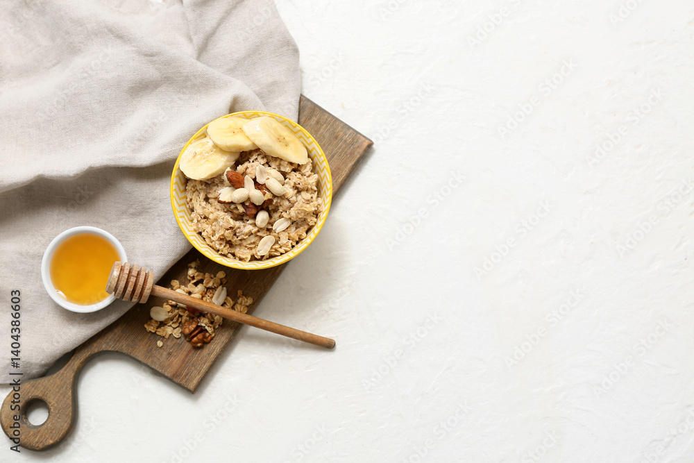 Bowl with tasty oatmeal, banana and nuts on white background