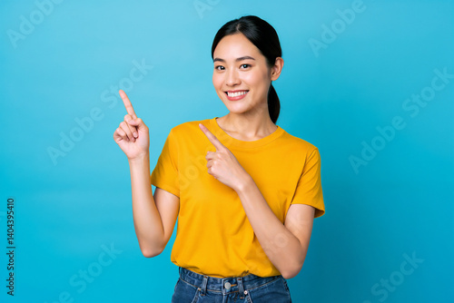 Happy Asian Woman Pointing Smiling Yellow Shirt Blue Background