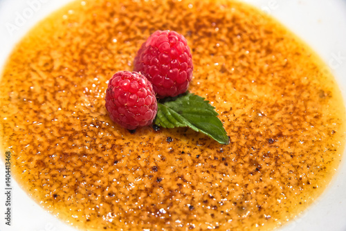 Fotografie Crème brûlée, a caramel-crusted dessert with raspberry, red berries, and crème b