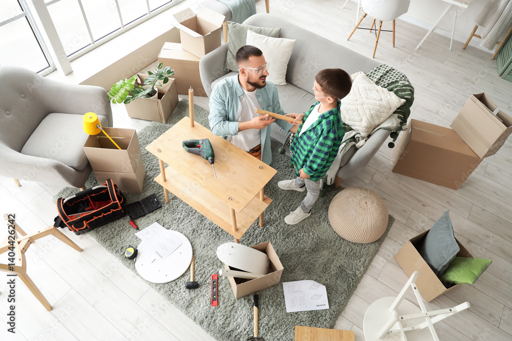 Father with his son assembling shelf unit at home, top view