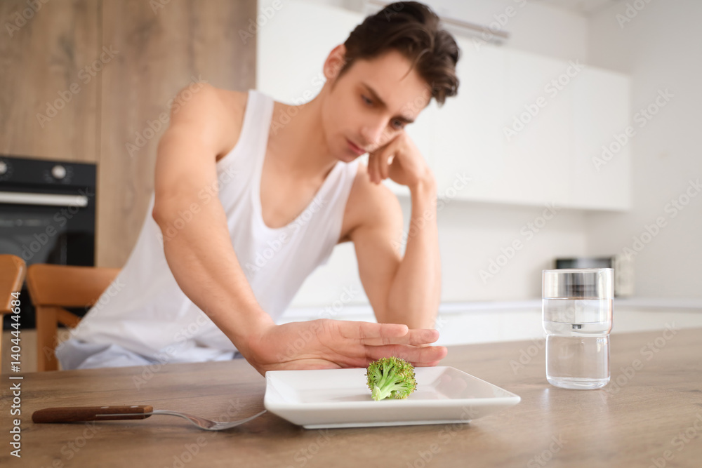 Young man with anorexia refusing from food in kitchen Young man with anorexia refusing from food in kitchen