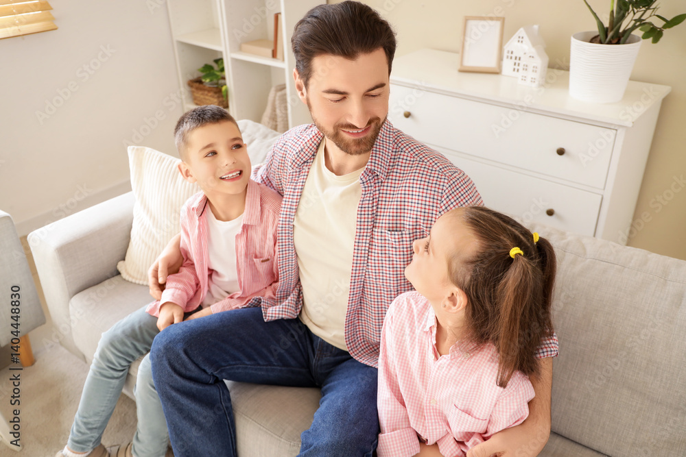Happy father hugging his little children on sofa at home Happy father hugging his little children on sofa at home