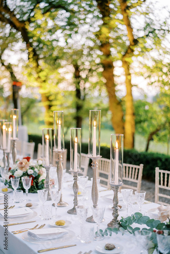 Festive table with lit candles and bouquets of flowers in the garden