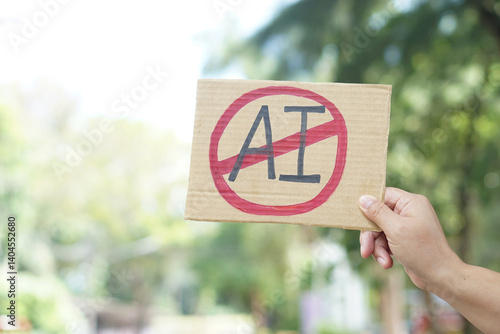 Close up hand holds paper card with No AI,  prohibition sign, outdoor nature background. Concept, disagree, anti or don't support to use AI or Artificial Intelligence in daily life.        
