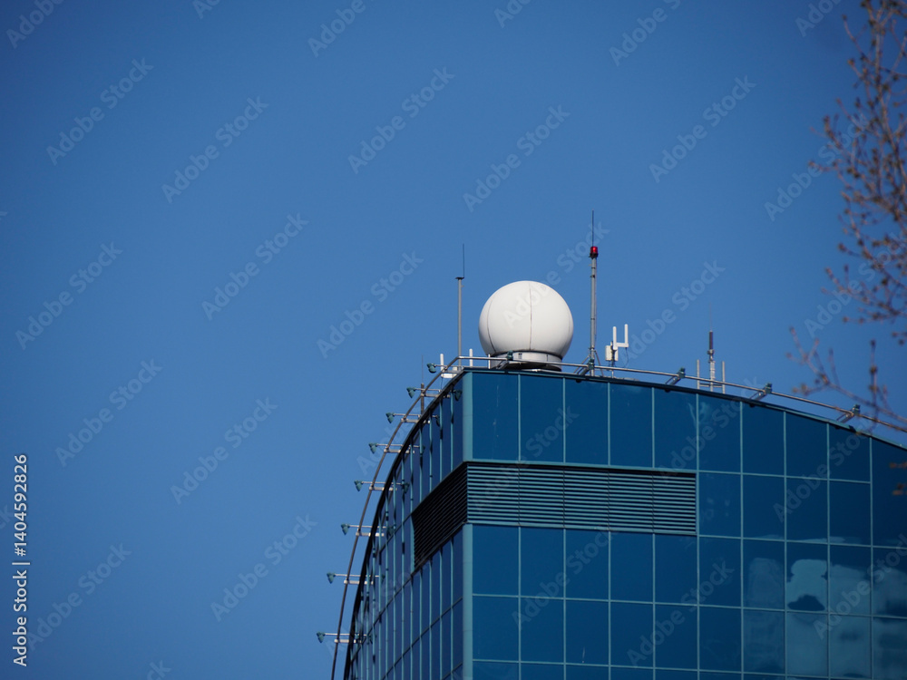 Obraz premium Modern Glass Office Building with Curved Facade Reflecting Blue Sky in Contemporary Urban Architecture