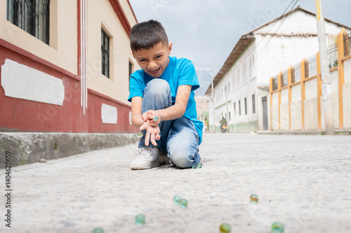 Enthusiastic latin american boy playing marbles in the street of a colonial town