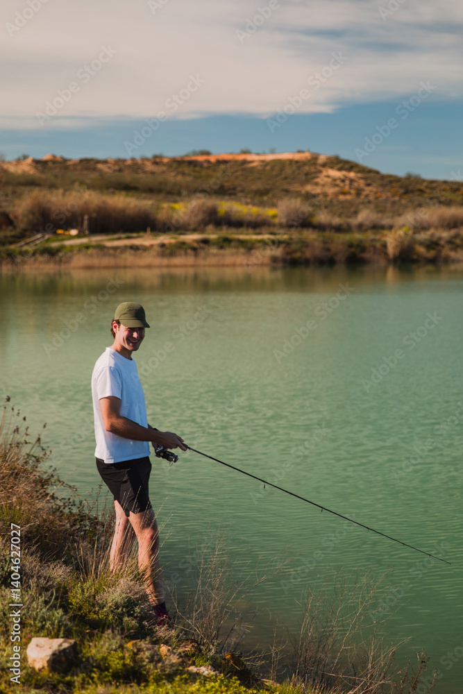 Young Man Fishing by a Peaceful Green Lake Young Man Fishing by a Peaceful Green Lake