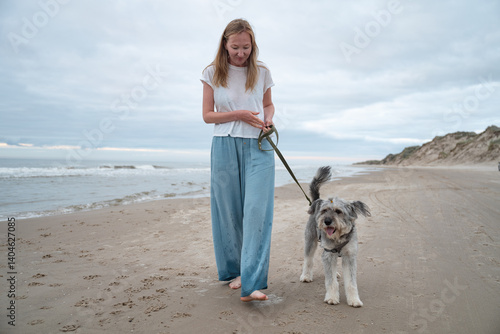 Φωτογραφία woman walking barefoot with her dog on beach of North sea, Denmark