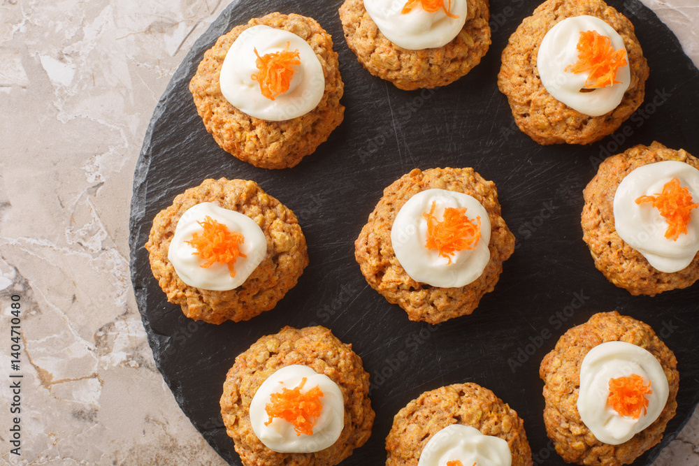 Diet gluten free carrot oatmeal cookies with cream cheese icing close-up on a plate on the table. Horizontal top view from above