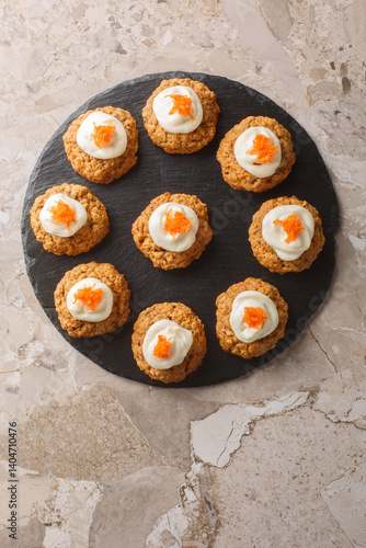 Healthy Carrot Oatmeal Cookies with Cheese Frosting Close-up on Plate on Table. Vertical top view from above
