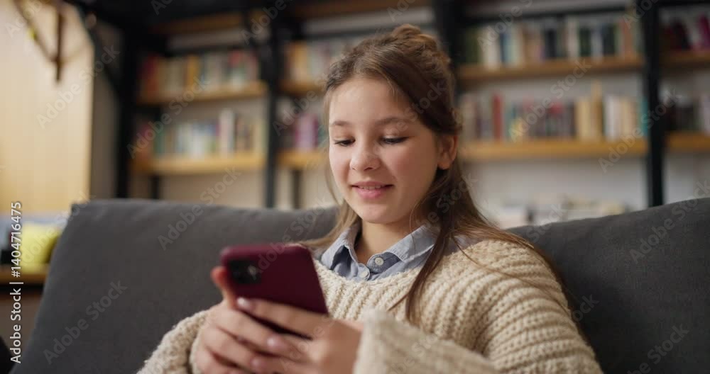 Girl is sitting on a couch and looking at her phone Girl is sitting on a couch and looking at her phone