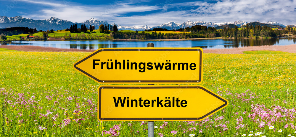 Ein Wegweiser zeigt in unterschiedliche Richtungen mit der Aufschrift Frühlingswärme und Winterkälte - FOTOMONTAGE