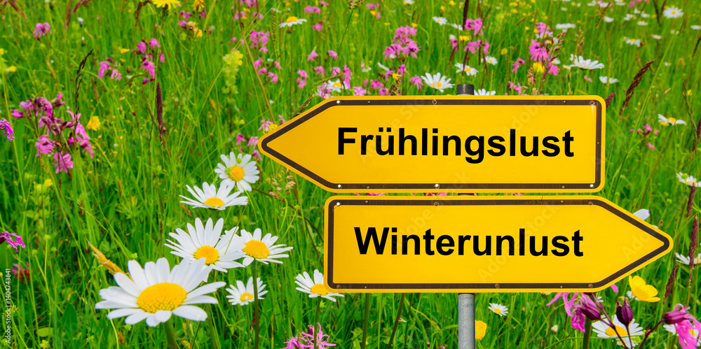 Ein Wegweiser zeigt in unterschiedliche Richtungen mit der Aufschrift Frühlingslust und Winterunlust - FOTOMONTAGE