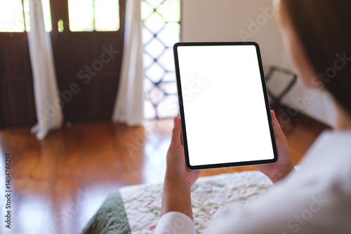 Obraz na płótnie Mockup image of a woman holding tablet with blank desktop white screen on the bed at home w salonie