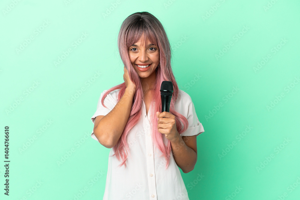 Young mixed race singer woman with pink hair isolated on green background laughing Young mixed race singer woman with pink hair isolated on green background laughing