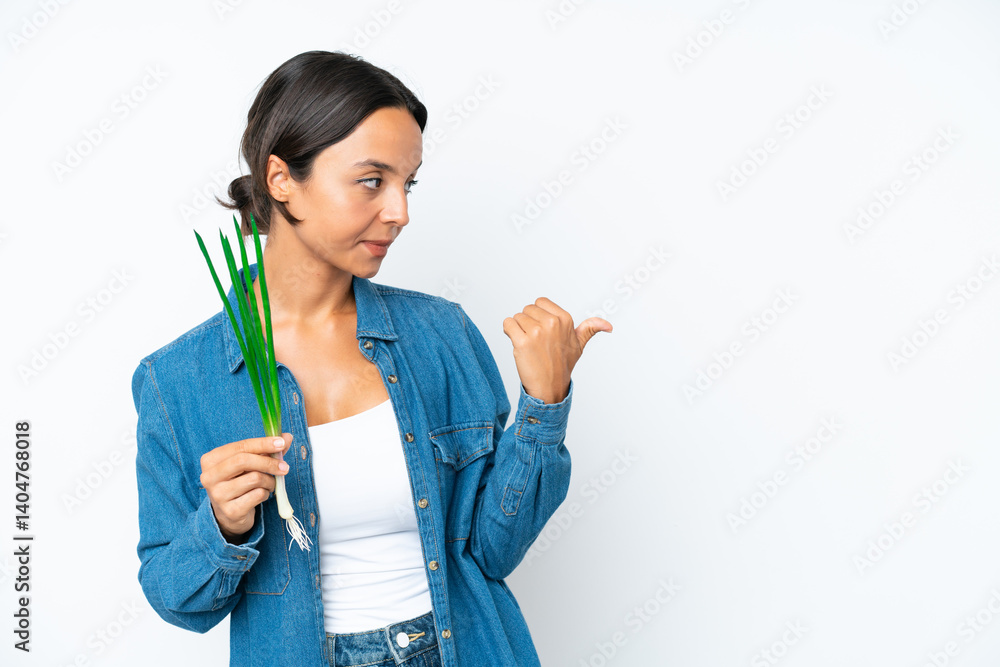 Young hispanic woman holding chive isolated on white background pointing to the side to present a product Young hispanic woman holding chive isolated on white background pointing to the side to present a product
