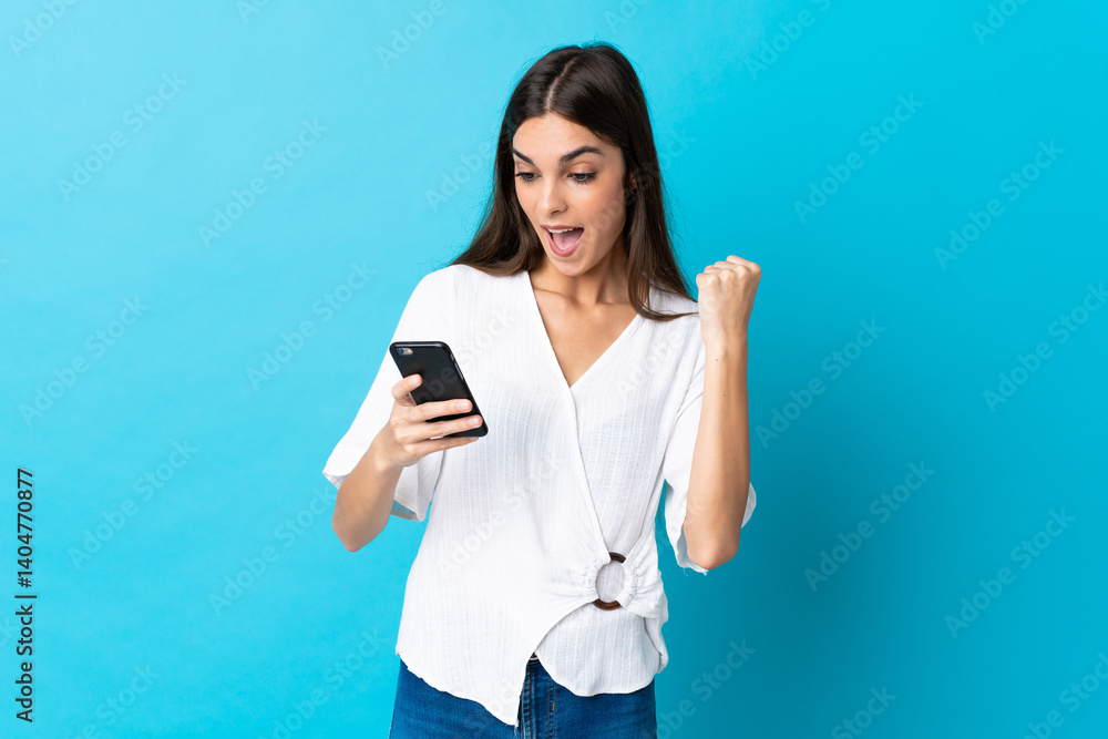 Young caucasian woman isolated on blue background surprised and sending a message Young caucasian woman isolated on blue background surprised and sending a message