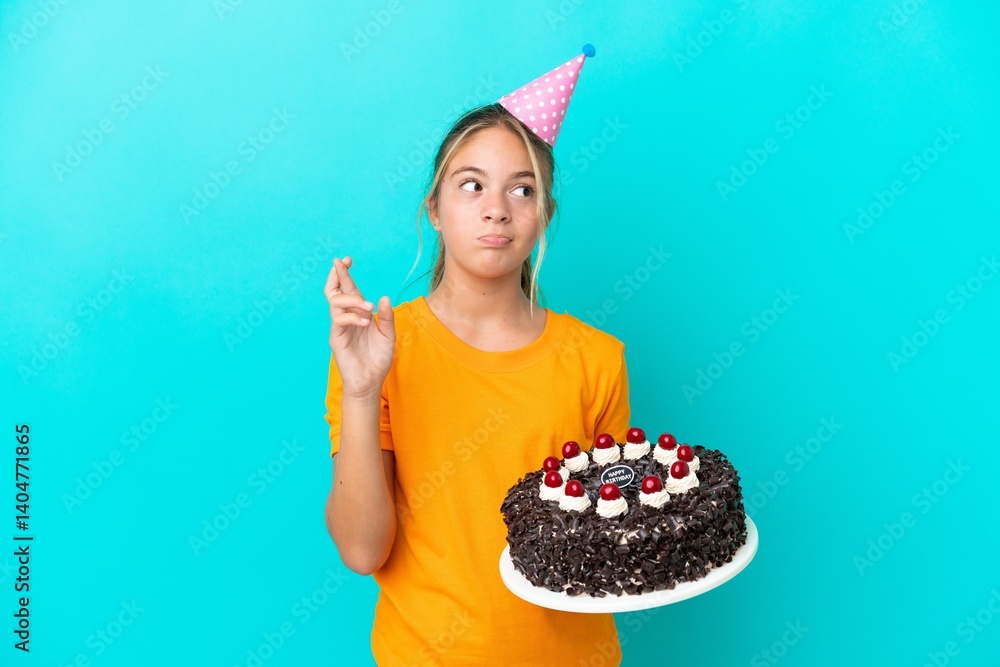 Little caucasian girl holding birthday cake isolated on blue background with fingers crossing and wishing the best Little caucasian girl holding birthday cake isolated on blue background with fingers crossing and wishing the best