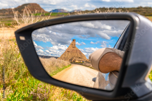 Leaving bardenas reales natural park in navarre, spain, reflected in rearview mirror