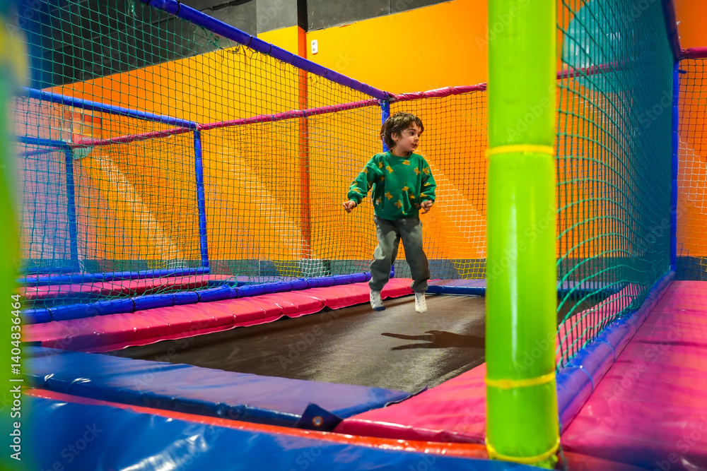 Child jumping and having fun on colorful trampoline in indoor playground