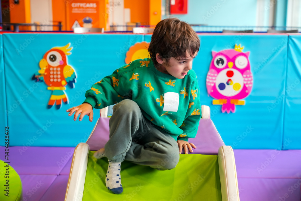 Child playing on soft slide in indoor playground