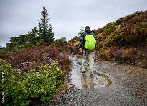Obraz na płótnie Backpacker hiking Taranaki Falls track in the rain. Tongariro National Park. New Zealand. w salonie