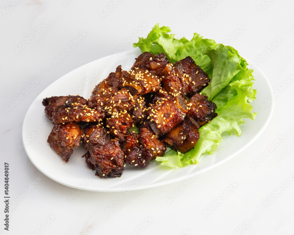 Close up of glazed pork pieces with sesame seeds on a white plate Close up of glazed pork pieces with sesame seeds on a white plate