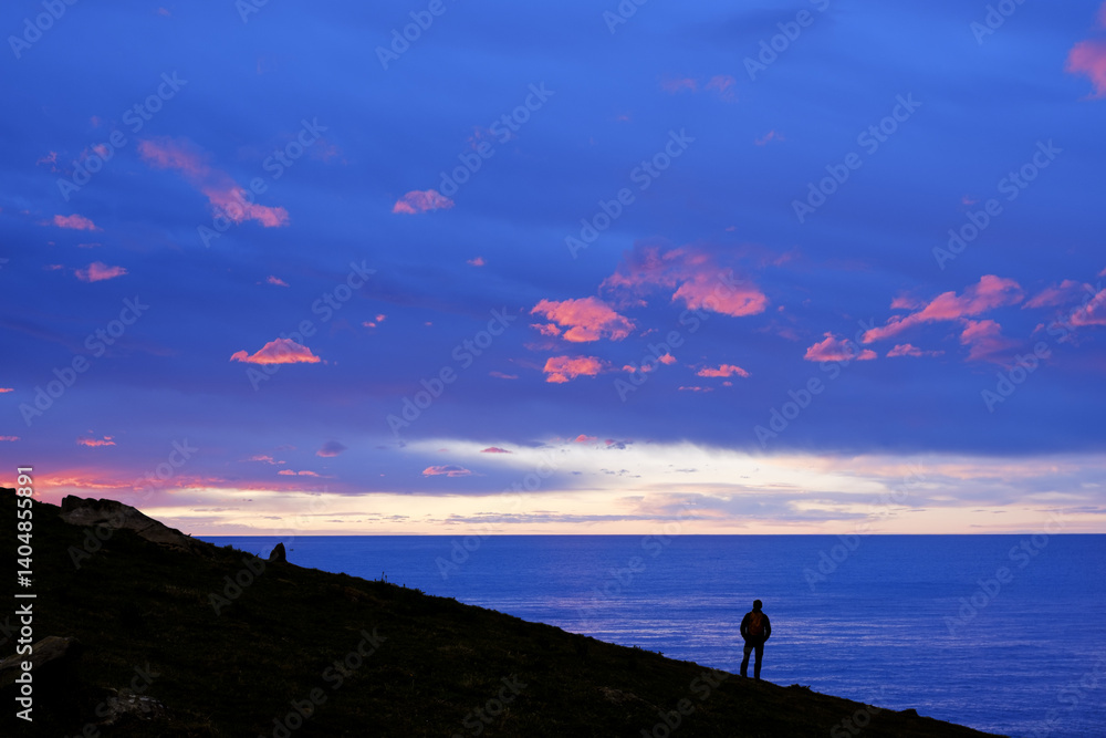 Hiker in front of the Cantabrian Sea at sunset, Euskadi