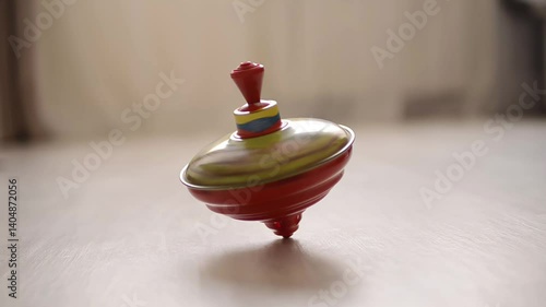 Colorful metal spinning top balancing in motion on a wooden floor with soft light

