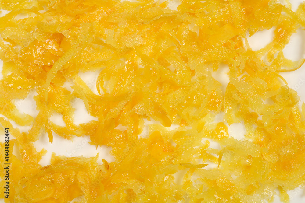 A close-up shot shows a pile of finely grated bright yellow lemon zest spread across a white surface A close-up shot shows a pile of finely grated bright yellow lemon zest spread across a white surface