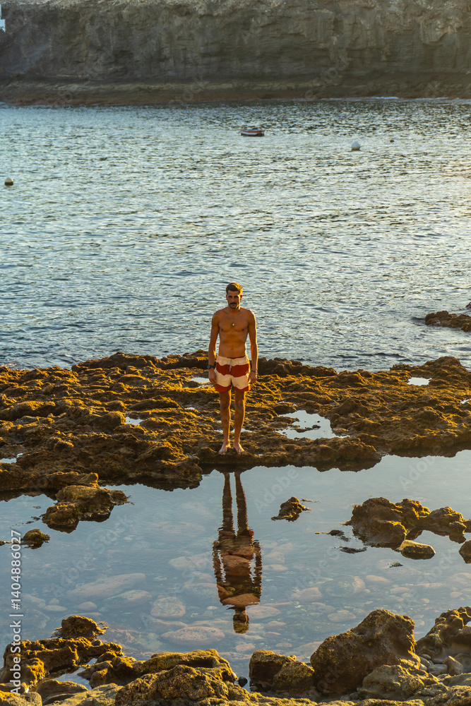 Tourist reflecting on volcanic rocks at tufia beach, gran canaria