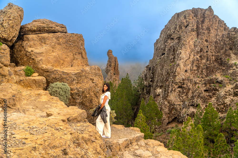 Tourist enjoying roque nublo during mountain hike in gran canaria, spain