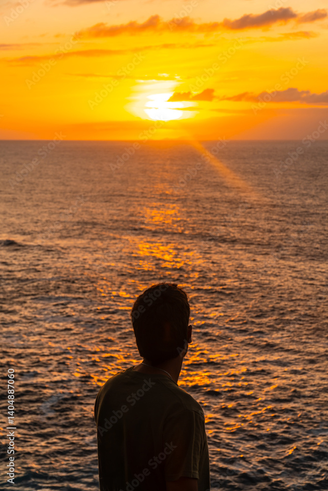 Tourist admiring stunning golden sunset over atlantic ocean in agaete, gran canaria
