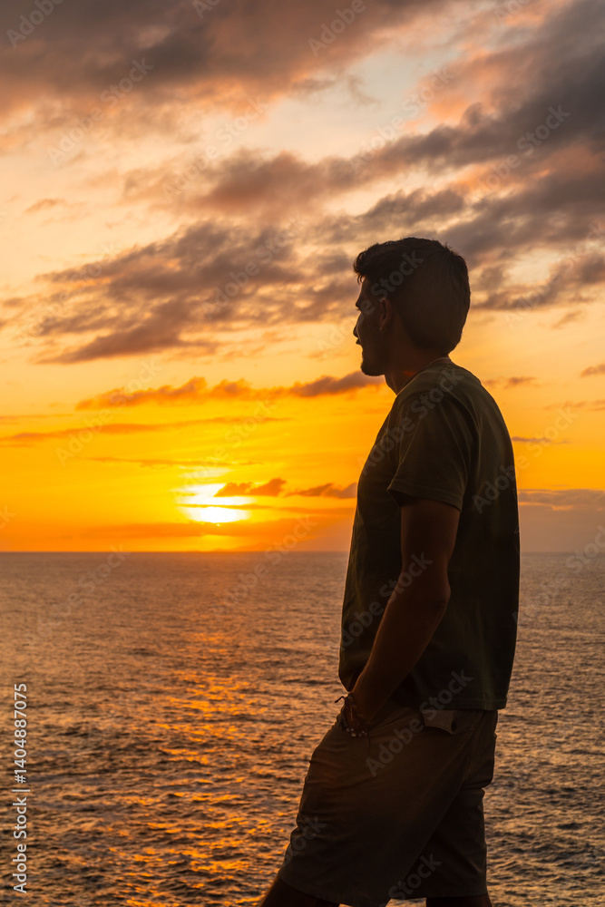 Tourist admiring stunning sunset over atlantic ocean in agaete, gran canaria