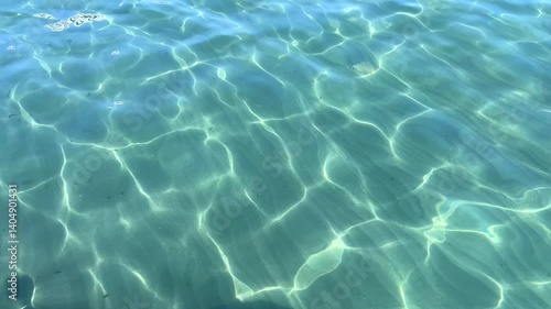Crystal-clear water reflecting sunlight, with gentle waves creating a soothing effect.