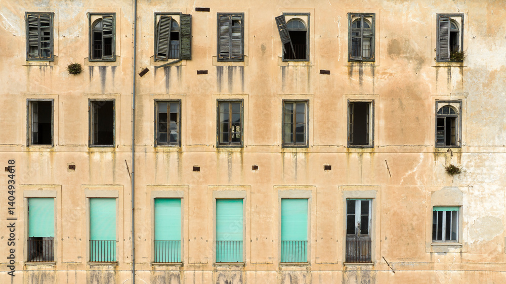 Facade of an old abandoned building with broken windows.