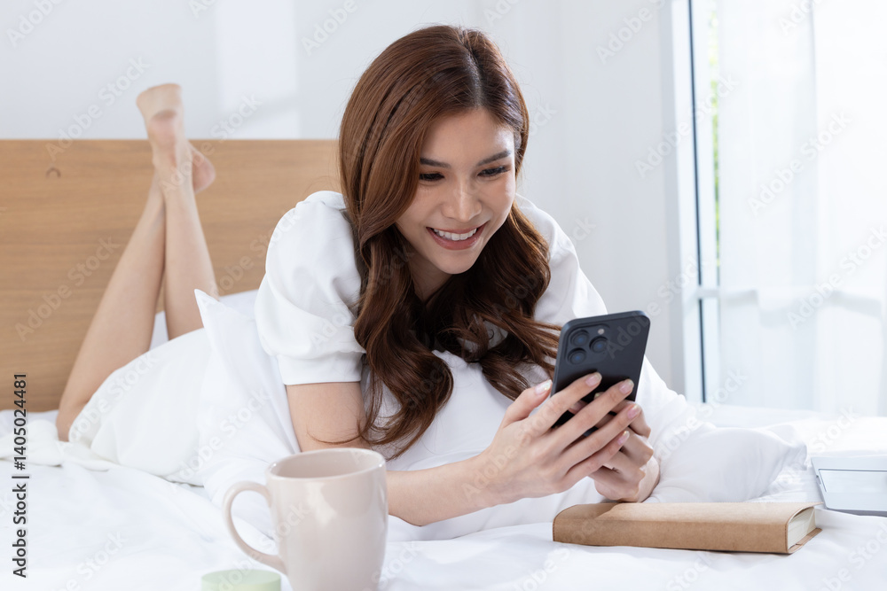 Smiling woman using smartphone while relaxing in bed Smiling woman using smartphone while relaxing in bed