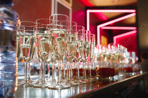 A beautiful row of elegant champagne glasses has been meticulously lined up on a stylish bar, ready to be filled and enjoyed