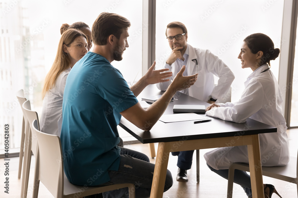 Fototapeta premium Challenge for patient health. Multiracial hospital team of medical professionals gather on staff conference engaged in case study analyze discuss symptoms treatment options exchange experience ideas