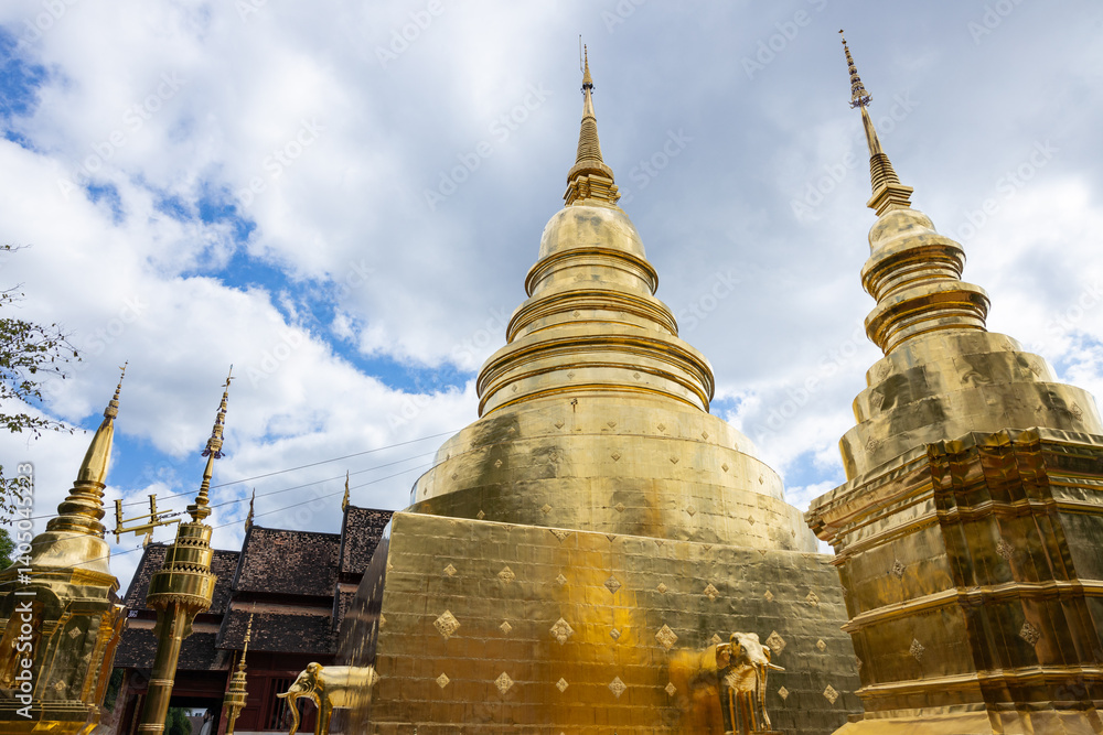 Fototapeta premium Golden pagodas at Thai temple under cloudy sky