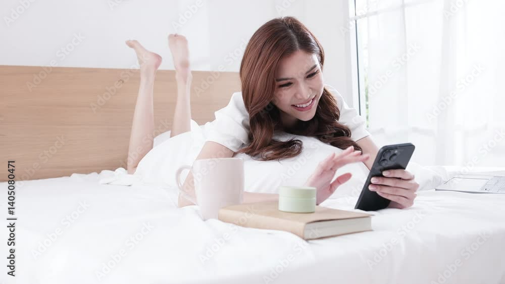 Smiling woman using smartphone while relaxing in bed Smiling woman using smartphone while relaxing in bed