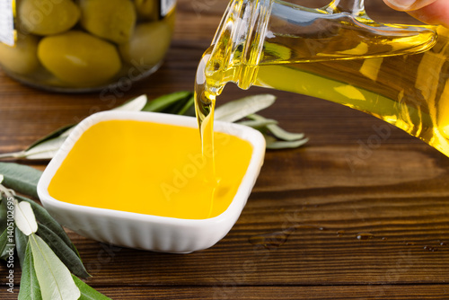 Obraz na płótnie Organic olive oil pouring from carafe into glass bowl w salonie