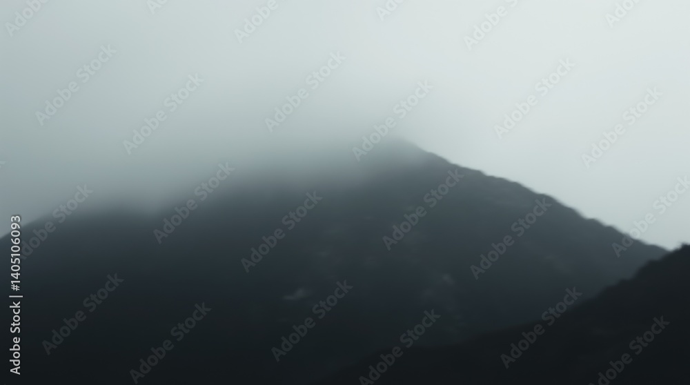 Misty mountain peak shrouded in dense fog on overcast day
