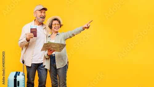 Fotografie Satisfied elderly husband and wife with map and passports posing on yellow studio background, pointing aside at free space