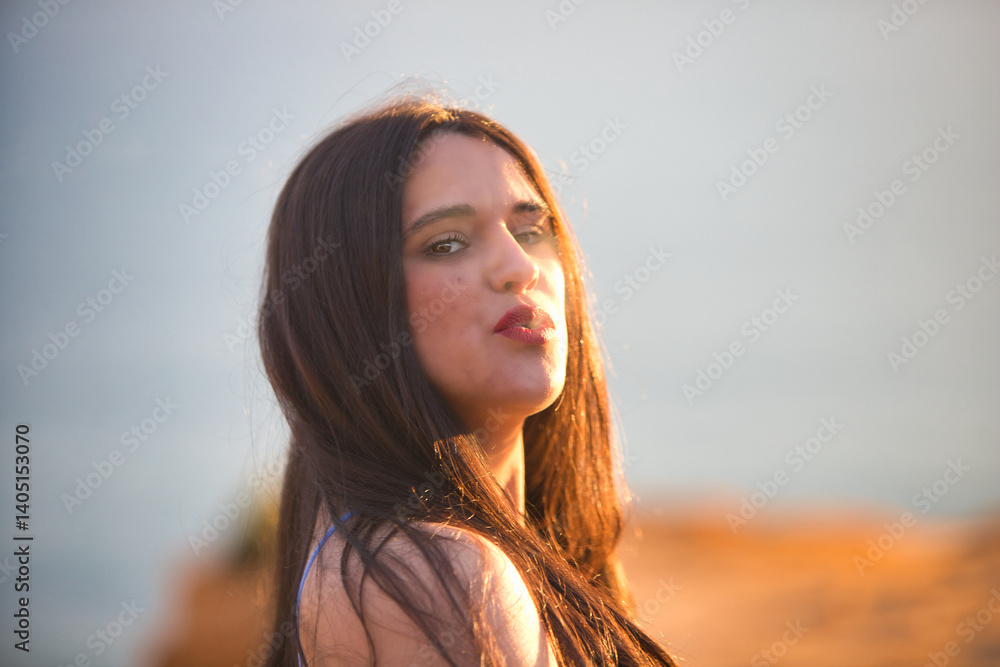 Young, Latin, brunette, beautiful woman smokes a cigarette and blows cigarette smoke in front of her. The woman stands on a cliff at sunset wearing blue underwear. Young, Latin, brunette, beautiful woman smokes a cigarette and blows cigarette smoke in front of her. The woman stands on a cliff at sunset wearing blue underwear.