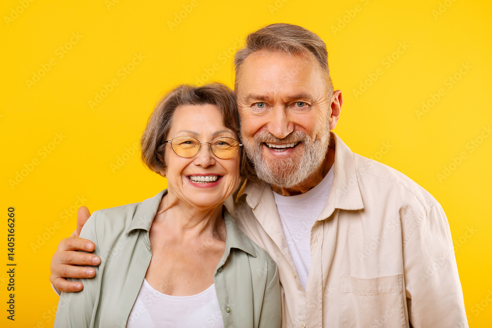 Portrait of loving senior man and woman in casual outfit posing on yellow studio background, embracing and smiling at camera. Happy marriage and retirement concept Portrait of loving senior man and woman in casual outfit posing on yellow studio background, embracing and smiling at camera. Happy marriage and retirement concept